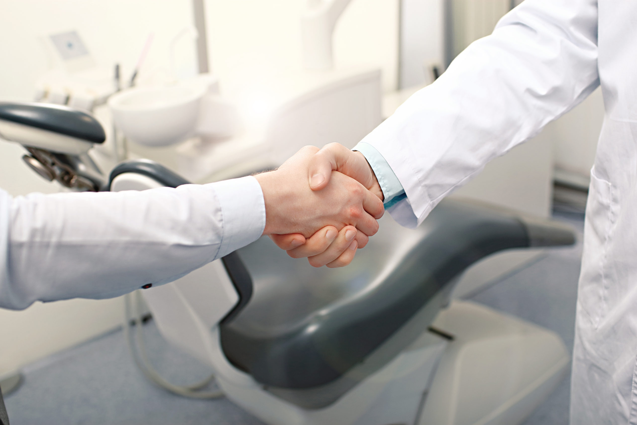Dentist shaking hands in front of dental chair