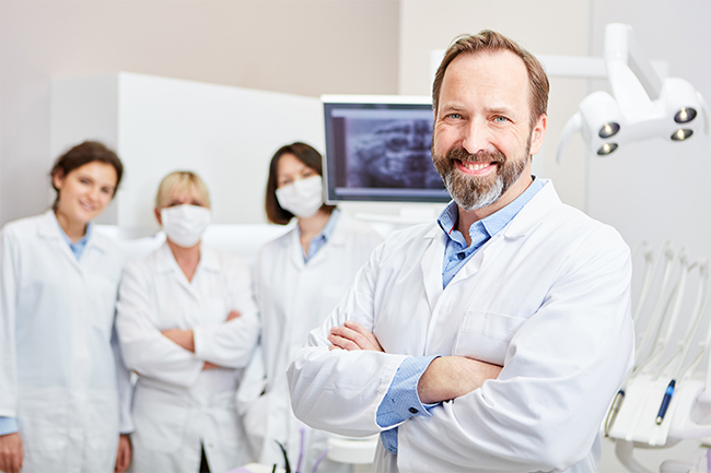 Dentist standing in office with staff
