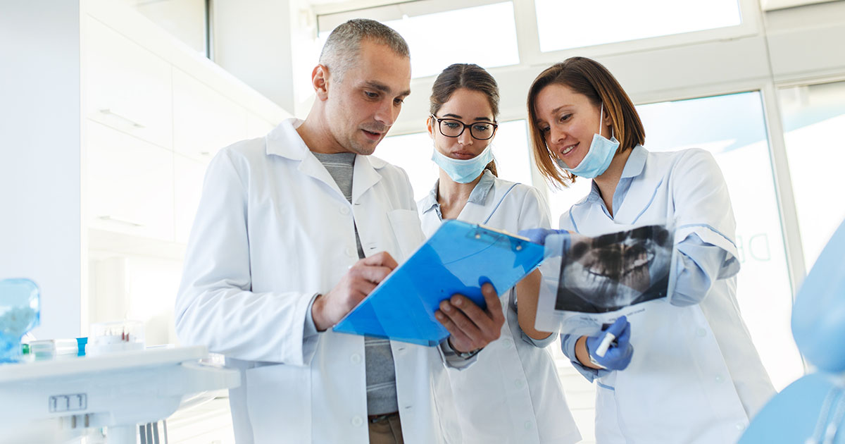 Three dental professionals in discussion