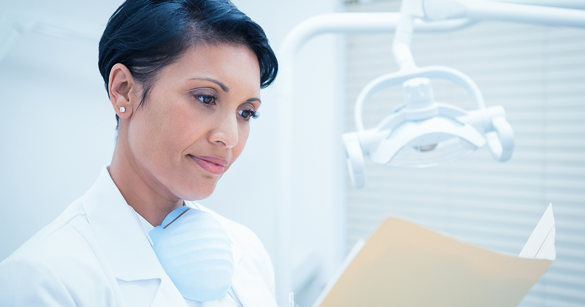 Female dental professional looks over documents. 