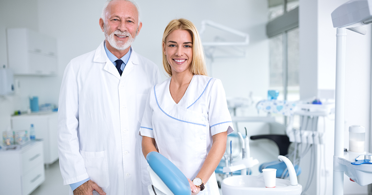 Two dental professionals standing in a dental office.