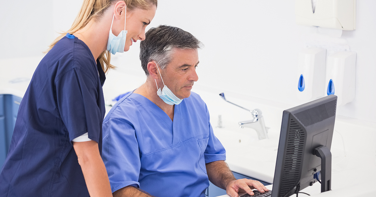 Two dental professionals looking over the accounts receivable on a computer. 