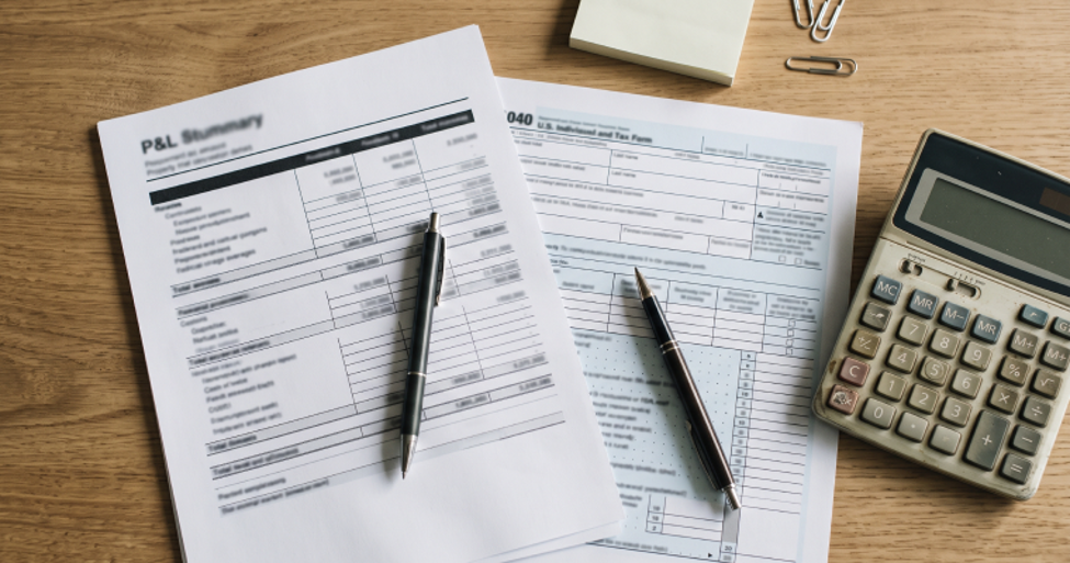 Profit and loss statement, tax form, and calculator on a desk
